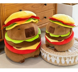 Two plush capybara toys wearing burger hats shown in large and small sizes on a wooden shelf