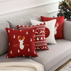 Christmas pillow covers with reindeer and trees on a grey sofa in festive home setting
