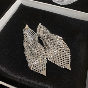 Detailed close-up of shiny silver metal mesh tassel earrings on black velvet jewelry box