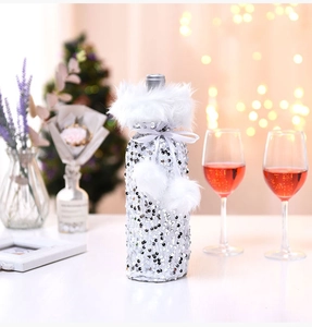 Close-up of silver sequin wine bottle cover with white plush trim and fuzzy pom-poms