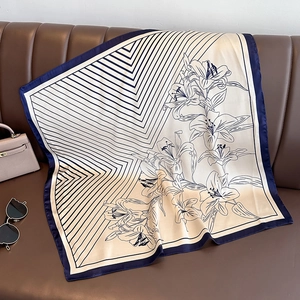 Flat lay of a striped silk scarf with floral patterns on a dark leather surface