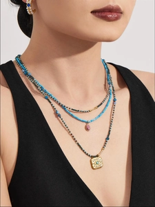 Close-up of layered turquoise necklaces with evil eye pendant and gold details