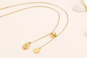 Detail of gold heart slider with religious relief and queen coin pendant necklaces