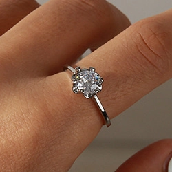 Close-up of elegant silver open ring with round clear zircon gemstone on a finger