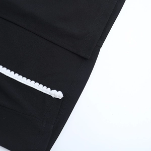 Détail d'une robe noire avec bordure en dentelle pompon blanche et coutures de précision