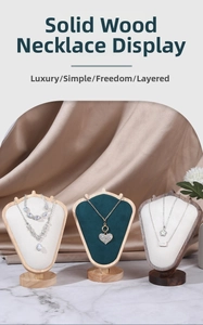 Three premium solid wood necklace display busts in walnut and velvet on marble surface