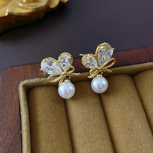 Detail of gold butterfly bow earrings with zircon stones and pearls on velvet