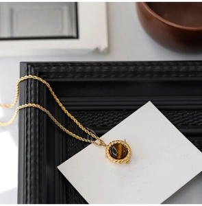 Detailed close-up of a vintage gold tiger eye stone pendant on a twisted rope chain