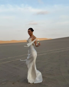 Elegant backless white satin dress featuring a cowl neck and thin straps in a desert setting
