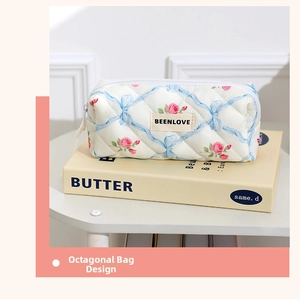 Detailed close-up of quilted floral cosmetic bag with pink roses and blue bow patterns