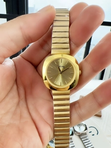Detailed close-up of a minimalist gold quartz watch with a metal elastic band on wrist