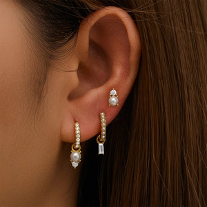 Close-up of three-piece 925 sterling silver gold earring set with pearls and zircons