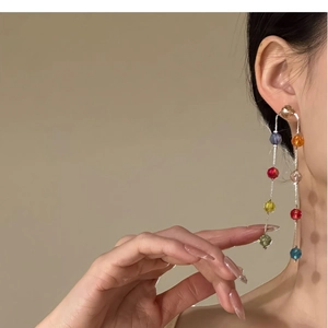 Detailed view of colorful glass bead tassel earrings on a model with silver needle posts