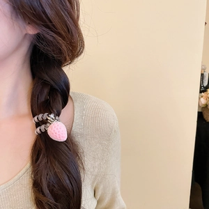 Charm fraise rose avec élastique spirale gris porté sur une longue tresse élégante
