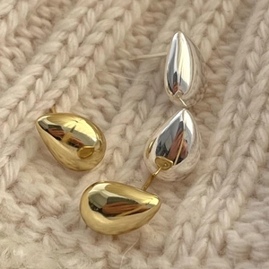 Minimalist teardrop metal stud earrings in gold and silver finish on knit fabric