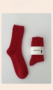 Close-up of red cotton socks with vertical ribbed texture and minimalist packaging