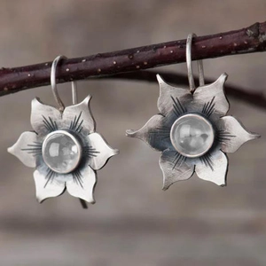 Gros plan de boucles d'oreilles fleurs en argent vintage avec pierres précieuses rondes