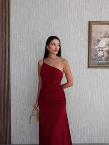 Detail of burgundy one-shoulder ruched dress with slim fit and elegant draping fabric