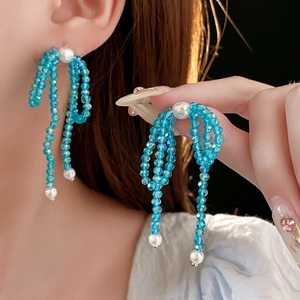 Detail shot of blue beaded bow earrings with sparkling crystal tassels and white pearls