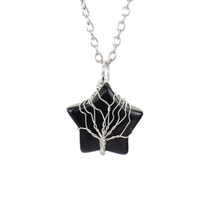 Macro view of star-shaped black stone pendant with silver tree of life wire wrapping