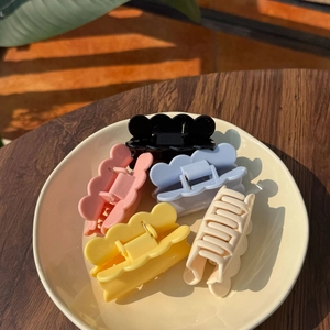 Close-up of five colorful matte hair claws neatly arranged in a ceramic bowl for display