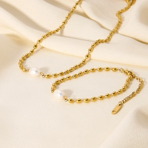 Golden titanium steel jewelry set with natural freshwater pearls on silk background