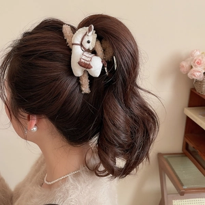 Detail of cute horse claw clip with plush fabric texture shown in a ponytail hairstyle
