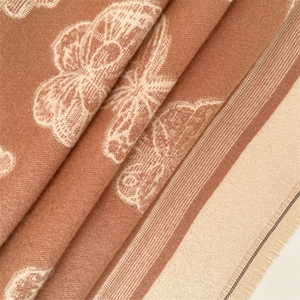 Detail of warm brown cashmere scarf showing elegant beige butterfly jacquard patterns