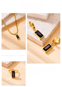 Detailed shot of golden necklace, earrings and ring set with black square faceted stones