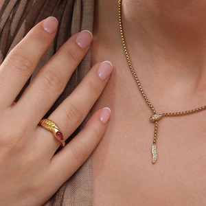 Detail of 18k gold plated snake ring and necklace set with red gemstone and zircons