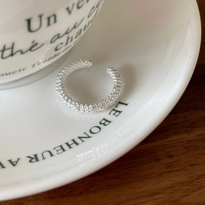 Macro detail of silver ring with popcorn bead texture on a white ceramic plate