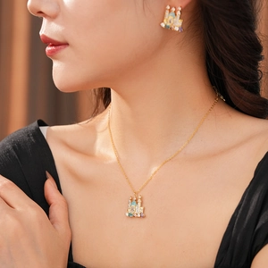 Close-up of gold plated castle pendant necklace and stud earrings set with zircon stones