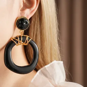Vintage geometric black resin earrings with gold wire wrap detail worn by model