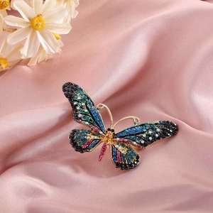 Detailed macro shot of a gold butterfly brooch with vibrant colorful rhinestones on silk