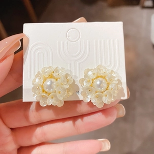 Close-up of pearl flower earrings with gold base and translucent white petals