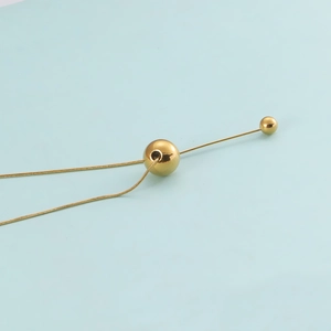Detailed view of a polished gold stainless steel sphere pendant with a stylish tassel bar