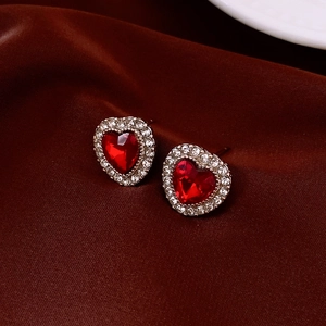 Gros plan de boucles d'oreilles cœur rouge avec diamants sur fond en soie rouge