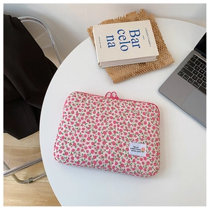 Detailed close-up of a pink floral quilted laptop sleeve with a zipper on a white desk