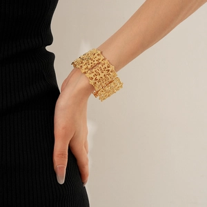 Macro detail of wide gold hollow floral lace bangle bracelet with retro ornate pattern