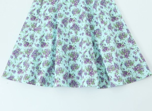 Detail of light blue floral poplin dress featuring purple flowers and fine fabric texture