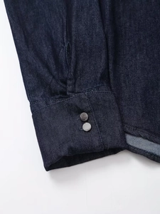 Gros plan des poignets de chemise en jean bleu foncé avec boutons-pression et coutures