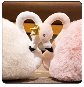 Close-up of white and pink swan plush toys with crowns forming a heart shape