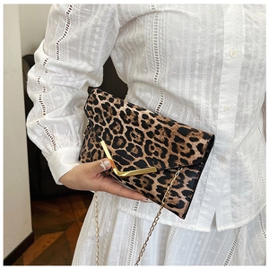 Detail of leopard print clutch featuring a gold V-shaped buckle and fine metal chain strap