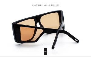 Close-up of modern flat top oversized sunglasses with amber lenses and black frame
