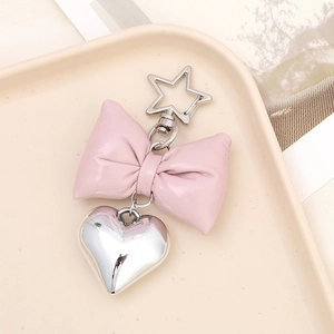 Pink faux leather bow keychain with silver heart charm and star-shaped metal clasp