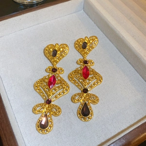 Dettaglio orecchini vintage a fiori dorati con gemme rosse in scatola di legno