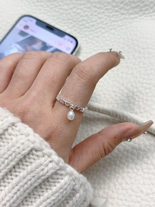 Detail of s925 silver hollow heart ring with hanging freshwater pearl on finger