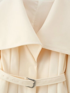 Detail von cremefarbenem Wollmantel-Revers und Taillengürtel mit silberner Schnalle