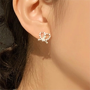 Close-up of a sterling silver twisted knot heart stud earring on a female ear model