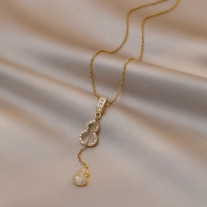 Détail macro d'un collier pendentif hulu doré avec zircons brillants sur fond de soie